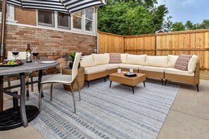 Eine Terrasse im Freien mit Esstisch, Stühlen, einer Couch und einem Couchtisch.