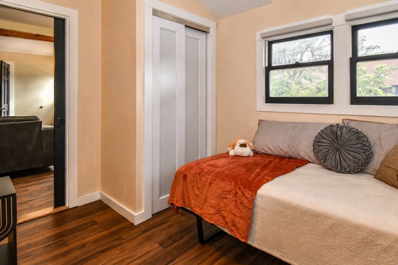 Ein Schlafzimmer mit Bett, Fenster, Tür und einem kleinen Tisch.