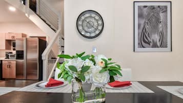 Un comedor con una mesa dispuesta para dos, un reloj de pared y una obra de arte con cebra enmarcada.