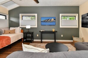 A modern bedroom with a bed, a desk, a chair, and a television on the wall. - SunHaven at Stone Ridge (Boulder)