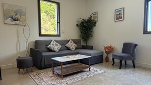 A living room with a grey sofa, a coffee table, a grey armchair, a potted plant, and a rug.