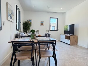 A dining area with a table set for four, surrounded by chairs, a television, and artwork on the walls.