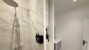 A bathroom with a shower, toilet, sink, and towel rack.