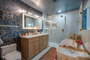 Een badkamer met een grote spiegel, een bad, een douche en een toilet.