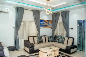A modern living room with a sectional sofa, a coffee table, and a painting on the wall. - The Haven | Modern 3BR En-suite Flat (Ibadan)