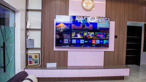 Ein moderner Empfangsbereich mit einem großen Flachbildfernseher an der Wand, einer Uhr und einem gerahmten Bild auf einem Regal.