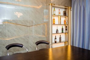 Eine Bar mit Regalen voller Flaschen, zwei Stühlen und einer Marmorwand.