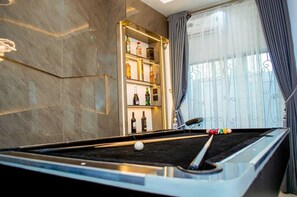 Ein Billardtisch mit Spielzeugkeule, einer Flasche Alkohol und einem Billardball.