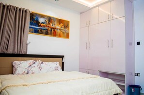 A hotel room with a bed, a wardrobe, and a painting on the wall. - The Haven | Modern 3BR En-suite Flat (Ibadan)