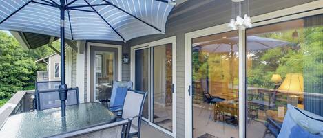 A covered patio area with a glass door leading to an outdoor seating area.