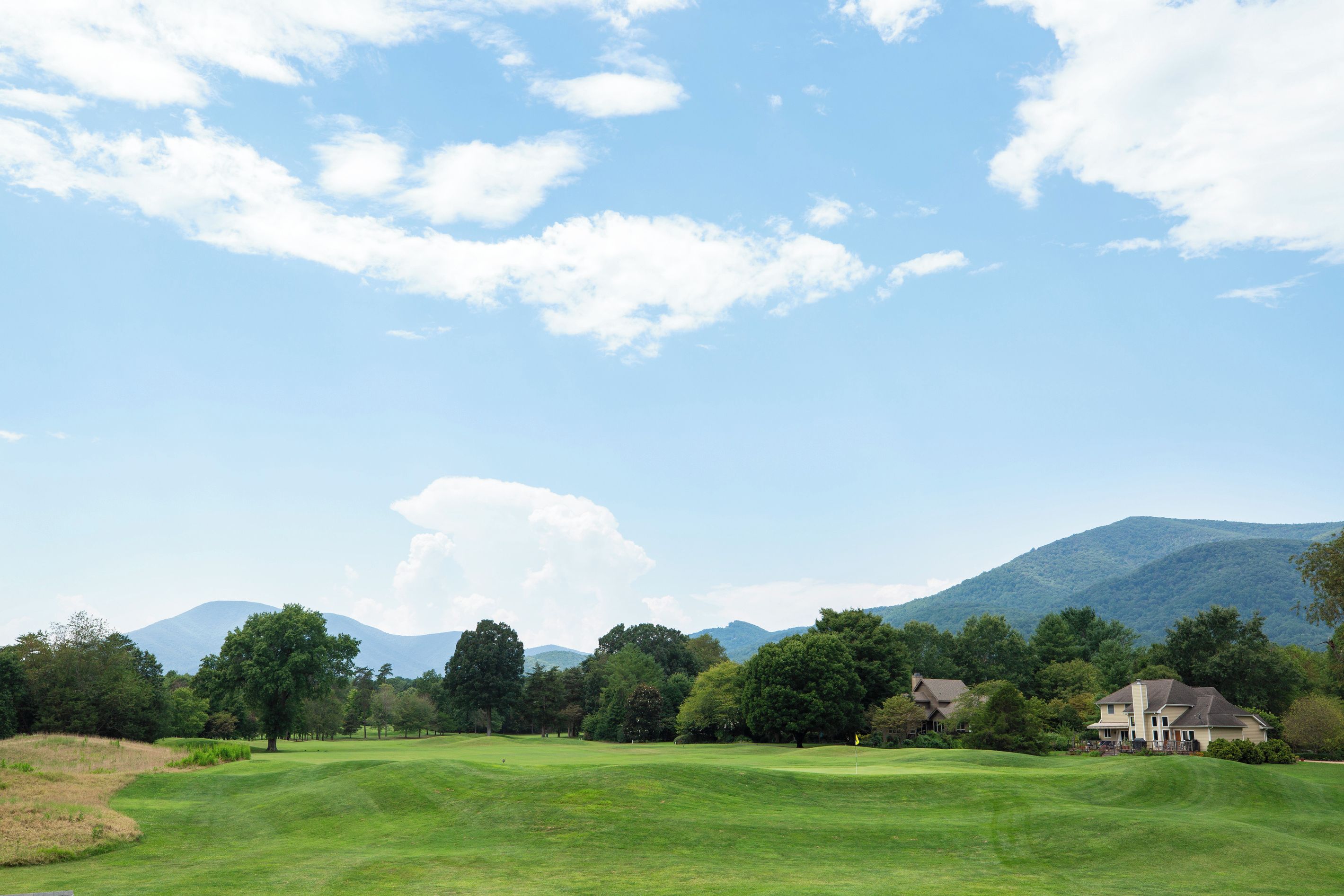 A golf course with a house in the background.