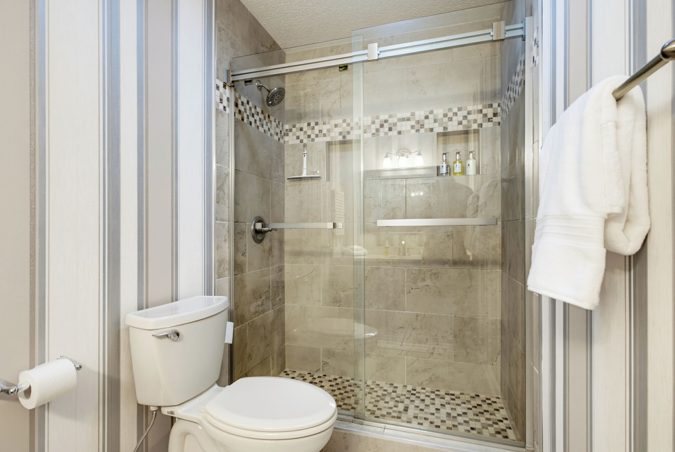 A bathroom with a glass-enclosed shower, a toilet, and a towel rack.