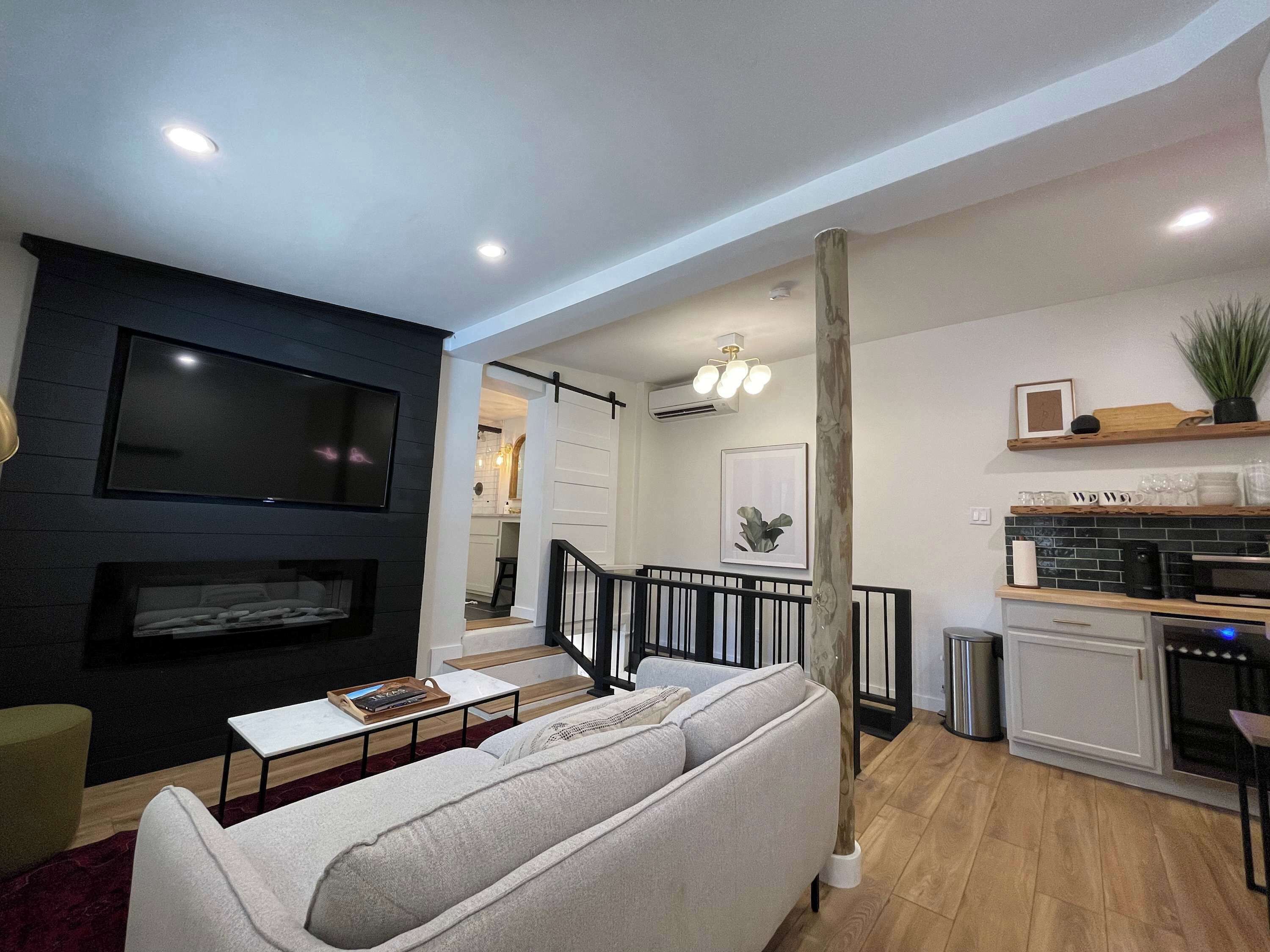 A modern living room with a sofa, a flat-screen TV, and a fireplace.