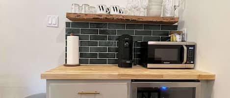 Una cocina compacta equipada con microondas, cafetera y un refrigerador pequeño.
