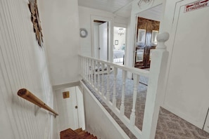 A staircase with white railings leading to a room with a bed and a window. - Pecan Grove Retreat - Pool & Fire pit (Fredericksburg)