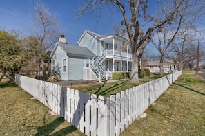 A two-story house with a porch and a fenced yard. - Pecan Grove Retreat - Pool & Fire pit (Fredericksburg)