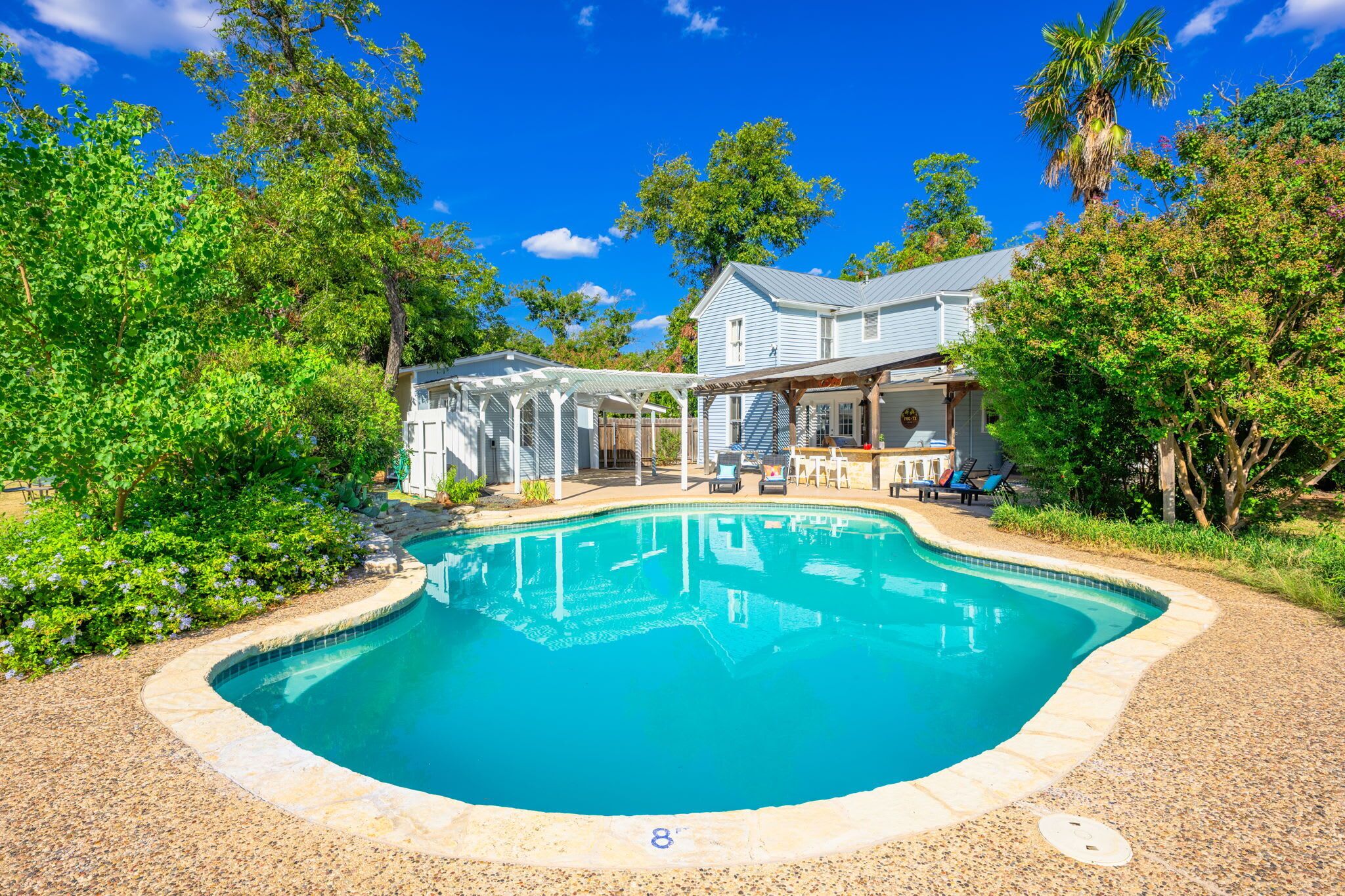 Un patio trasero con piscina, un porche cubierto y una casa con veranda.