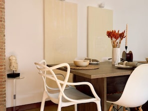 A dining area with a wooden table, white chairs, and a vase with dried flowers. - 2-bedroom apartment in beautiful El Poblado Medellín with AC (Medellín)