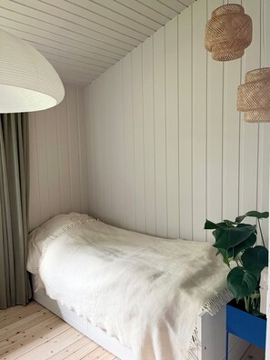 A room with a bed, a large white lamp, and two wicker wall sconces. - Classic Danish summer house (Asnæs)