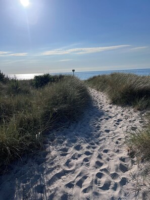 A sandy path leading to the sea with footprints and grass on either side. - Classic Danish summer house (Asnæs)
