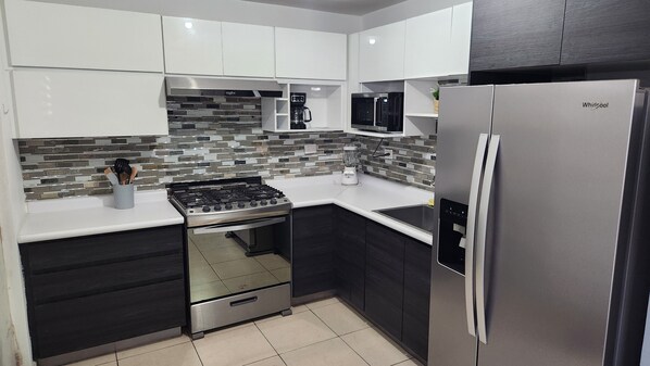 Una cocina moderna con estufa a gas, microondas y refrigerador de acero inoxidable.