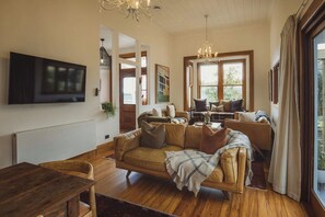 Ein gemütliches Wohnzimmer mit einer Couch, einem Couchtisch und einem an der Wand befestigten Fernseher.