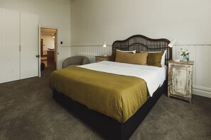 Ein Schlafzimmer mit einem Bett, einem Sessel, einem Nachttisch und einem kleinen Schrank.