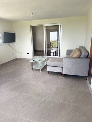 A modern living room with a grey sofa, a glass coffee table, and a flat-screen TV mounted on the wall. - Rico Puerto Magic Spot Oeste (Cabrera)