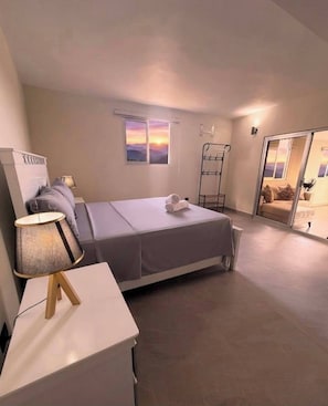 A bedroom with a bed, a bedside table, a lamp, a window with a view, and a sliding door leading to another room. - Rico Puerto Magic Spot Oeste (Cabrera)