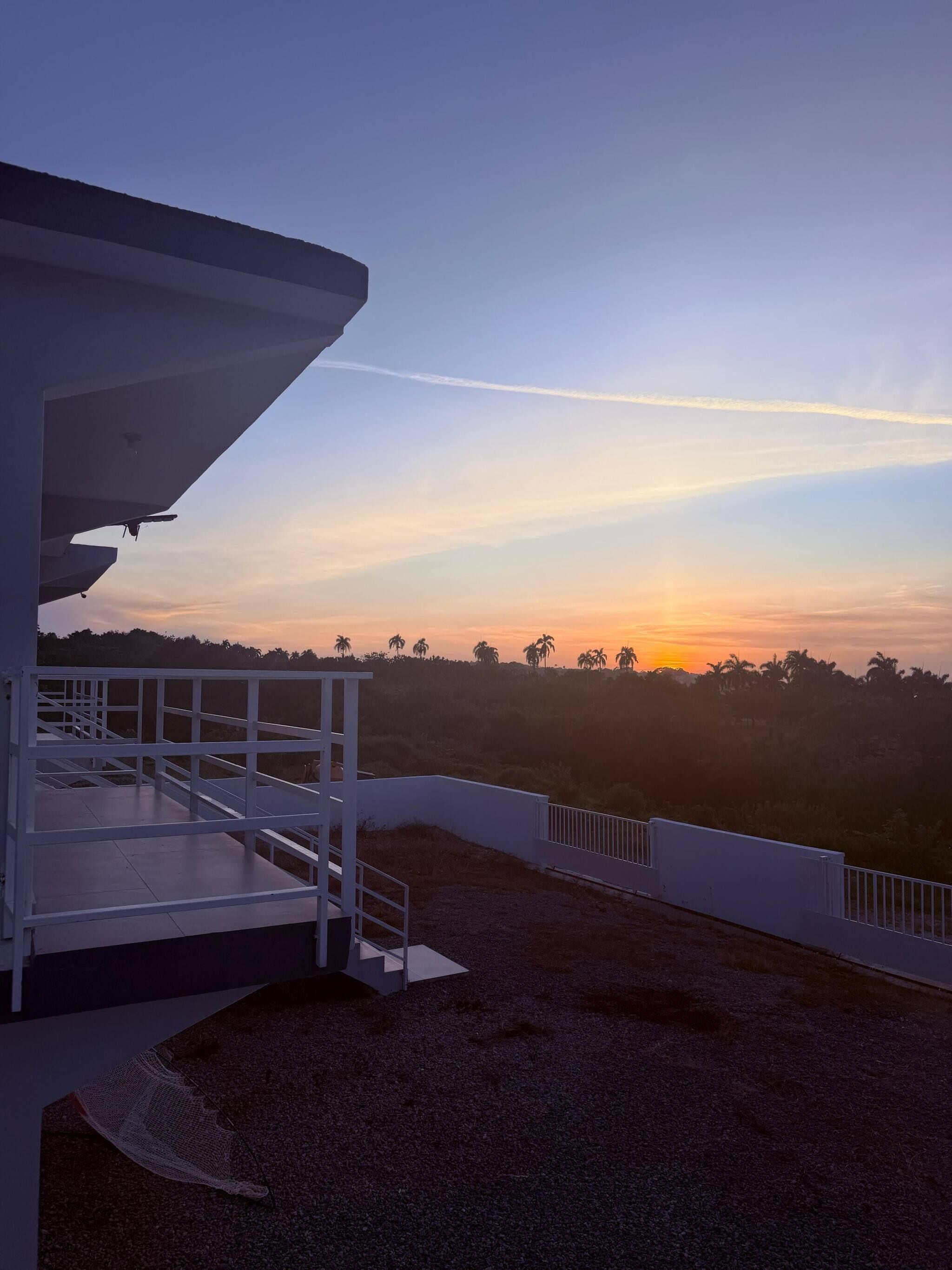 A building with a balcony overlooking a sunset.