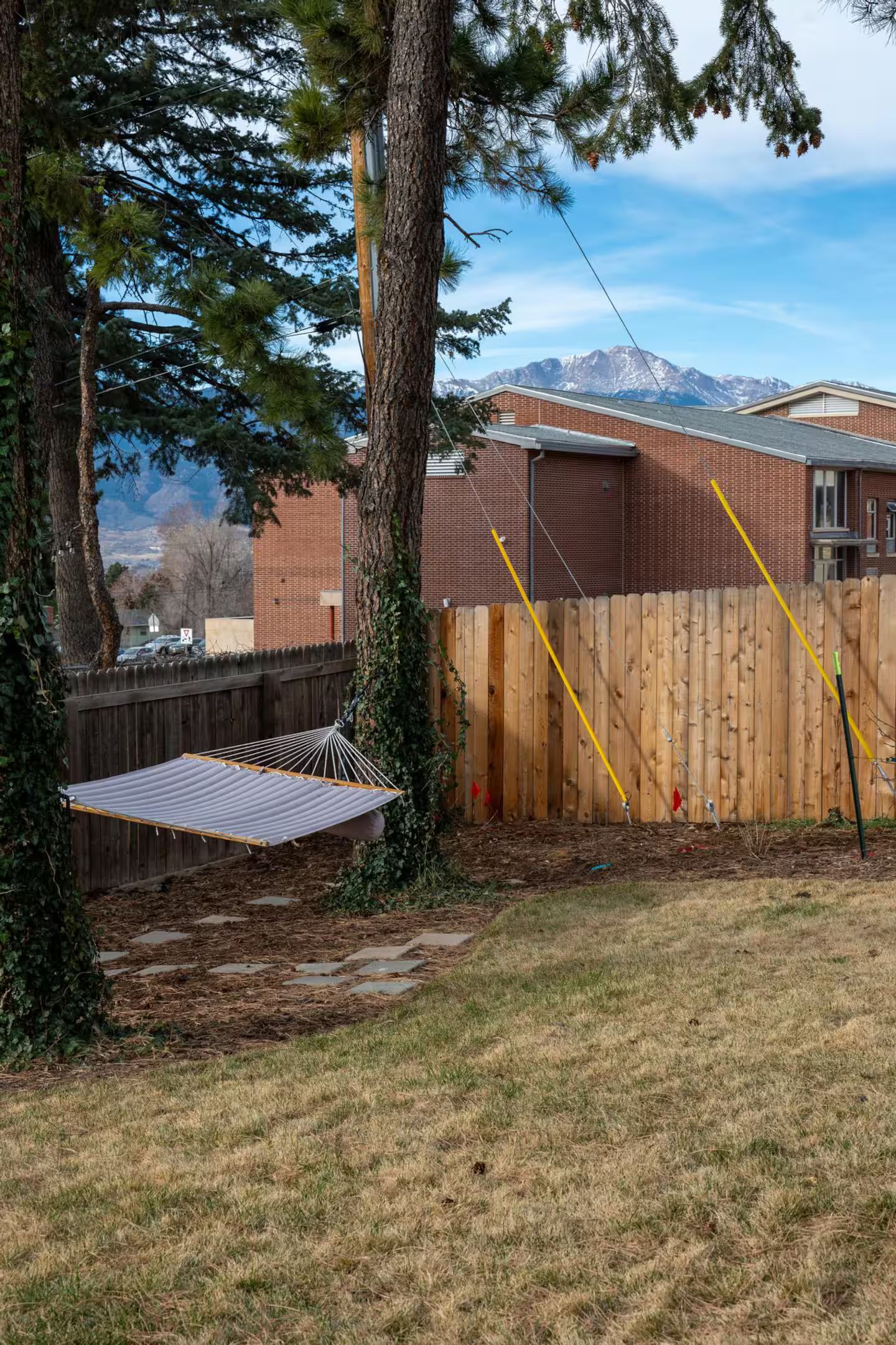 Un jardin avec une clôture en bois, un hamac et une vue sur les montagnes.