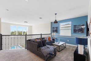 A modern living room with a grey sofa, coffee table, and a view of a swimming pool. - ViLla dReaMs PoOl +Game Room NeAr DiSnEy (Kissimmee)