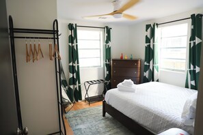 A bedroom with a bed, a dresser, a radiator, and a drying rack. - Modern Starland 2BR Courtyard + Parking (Savannah)