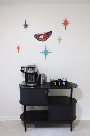 A coffee station with a coffee maker, a mug, and a coffee bar sign. - Modern Starland 2BR Courtyard + Parking (Savannah)