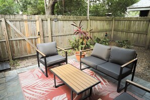 A patio area with a wooden table and two grey sofas. - Modern Starland 2BR Courtyard + Parking (Savannah)