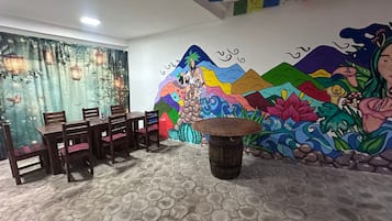 Un comedor con un mural, baldosas hexagonales en el suelo y sillas de madera.