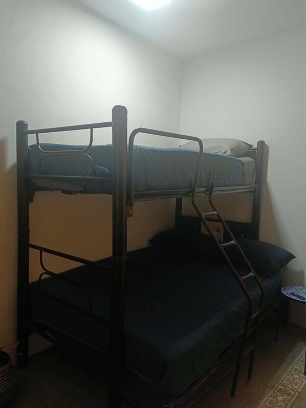 Una cama individual en literas en una habitación con una pequeña mesa y una silla.