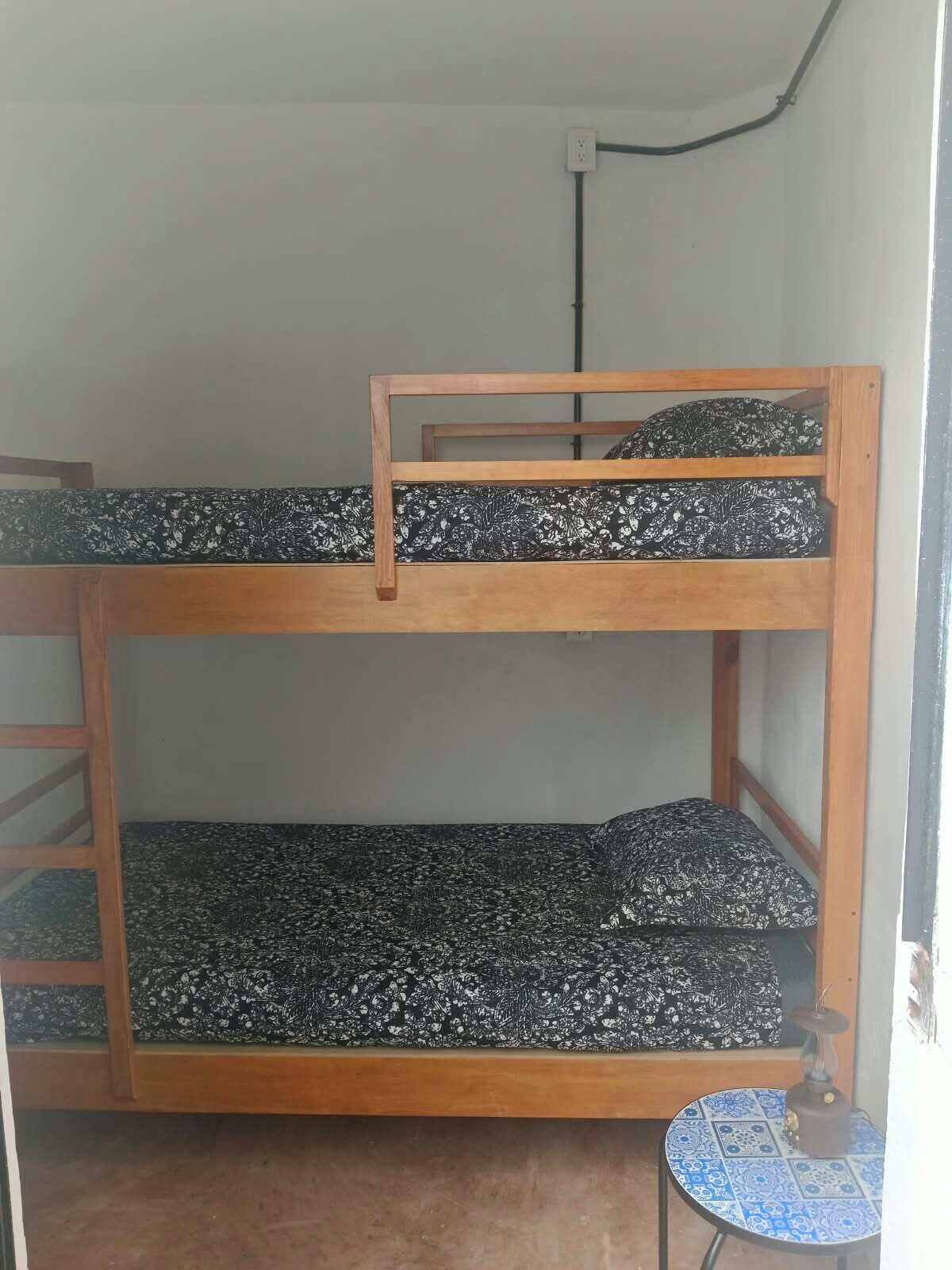 Een stapelbed met houten frame en beddengoed met een patroon.