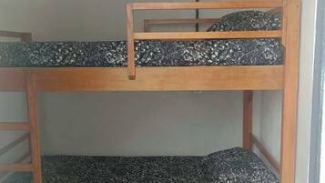 Een stapelbed met houten frame en beddengoed met een patroon.
