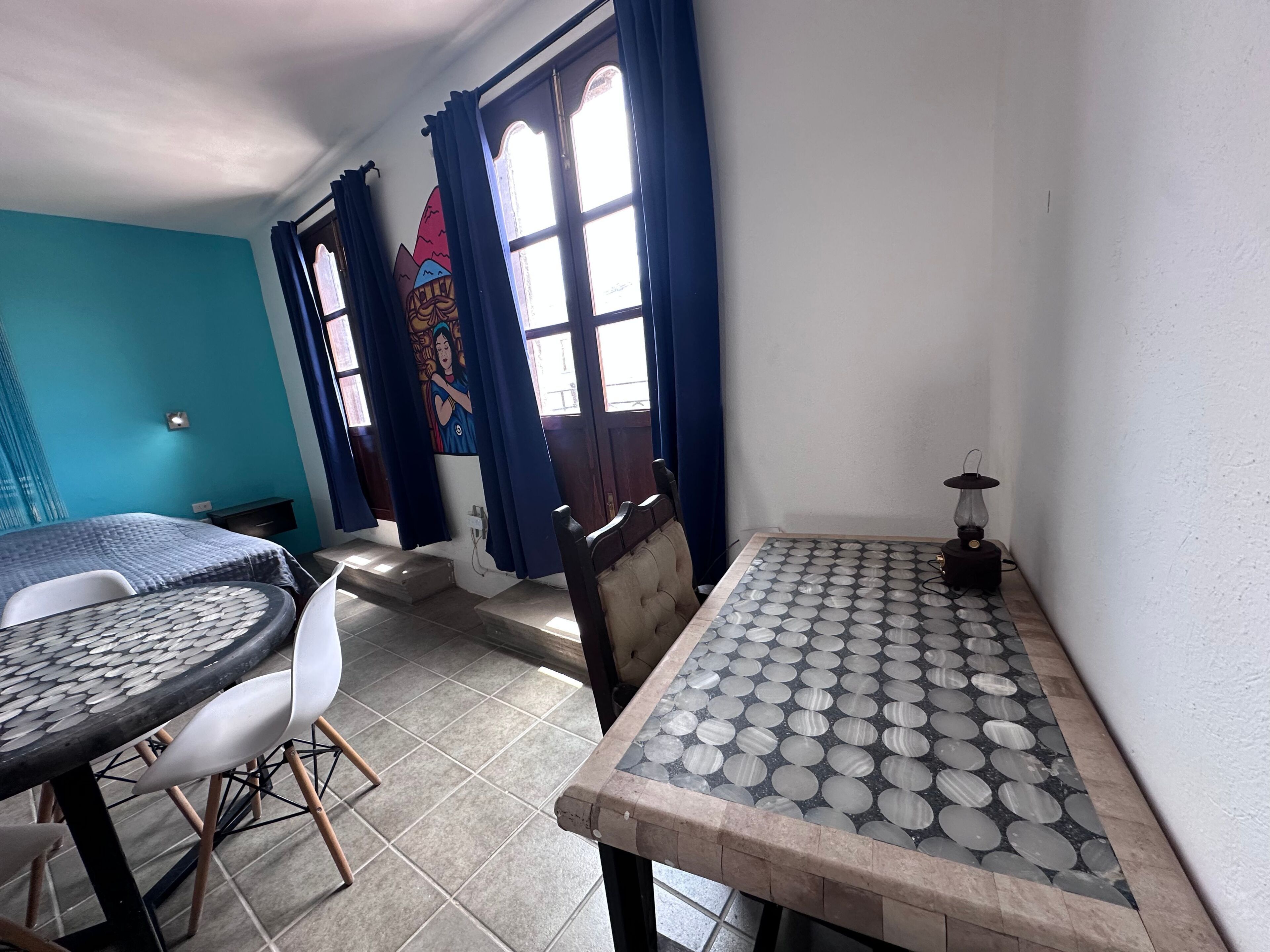 Une pièce comprenant une table à manger, des chaises, une petite table avec un plateau décoré, et un luminaire fixé au mur.
