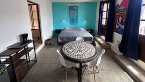 Een kamer met een bed, een tafel met een uniek patroon op het blad, een koffiezetapparaat en een aan de muur bevestigde projector.