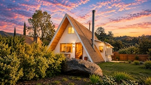 A modern house with a sloped roof, a chimney, and a well-maintained garden.