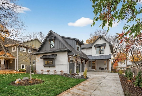 A two-story house with a covered front porch, a driveway, and a well-maintained lawn.
