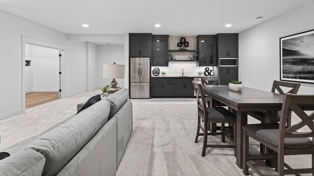Eine moderne Küche mit dunklen Schränken, einem Edelstahlkühlschrank und einem Essbereich mit Holztisch und Stühlen.