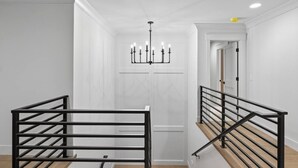 Ein modernes Interieur mit Treppe, schwarzen Metallgeländern und einer Chandelüster.