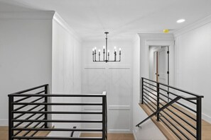 Ein modernes Interieur mit Treppe, schwarzen Metallgeländern und einer Chandelüster.