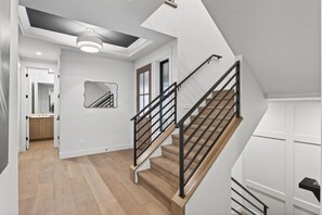 A modern interior with a staircase, a ceiling light, and a door.