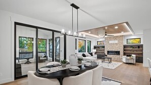 Ein modernes Wohnzimmer mit Essbereich, großen Fenstern, einem Kamin und einer Wand mit Steinverkleidung.
