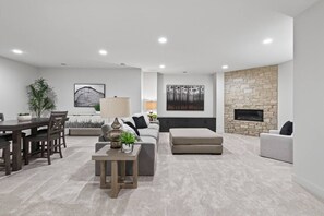 A modern living room with a fireplace, a dining area, and a seating area with a sofa and ottoman. - Brand New Home in Downtown Wayzata! (Wayzata)