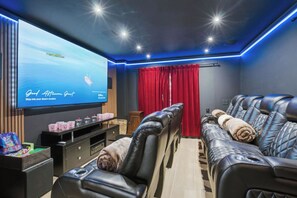 A room with a massage chair, a television, and a red curtain. - 5bd Home w/ Pool, Home Theater, Kayak & Golf cart (Indian Rocks Beach)